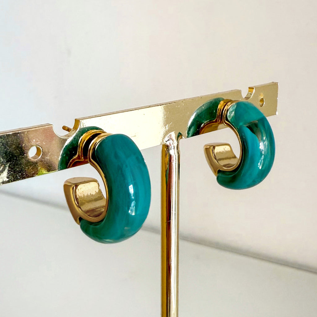 Aros Zuri de acero inoxidable y resina en exhibición, color verde con detalles dorados.